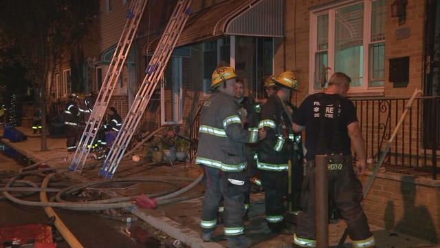 Firefighters stand near a rowhome in Philadelphia 