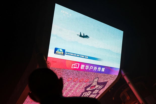 A tela mostra imagens noticiosas de exercícios militares conduzidos em áreas ao redor da ilha de Taiwan pelo Comando do Teatro Oriental do ELP chinês, em Pequim.
