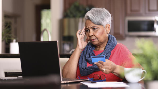 Senior adult woman frustrated paying bills at home. 