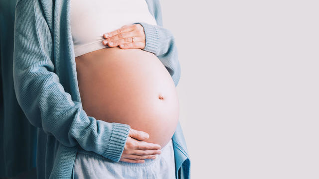 Pregnant woman holds hands on her belly.  Pregnancy, maternity, preparation and expectation concept. 