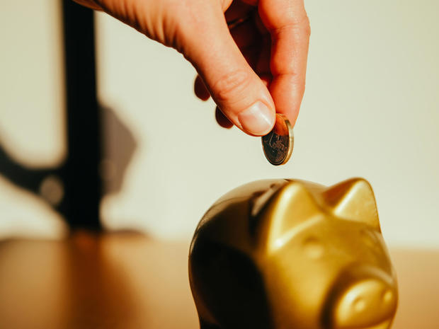 Putting a coin in a golden piggy bank. 