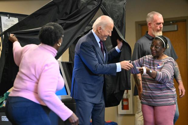 President Biden is handed an I Voted sticker as he steps out of the voting booth after casting his early voting ballot in the 2024 general election in New Castle, Delaware, on Oct. 28, 2024. 