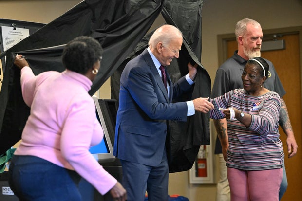 President Biden is handed an I Voted sticker as he steps out of the voting booth after casting his early voting ballot in the 2024 general election in New Castle, Delaware, on Oct. 28, 2024.