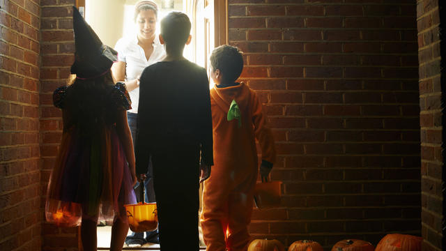 Rear view of three children wearing halloween costumes trick or treating 