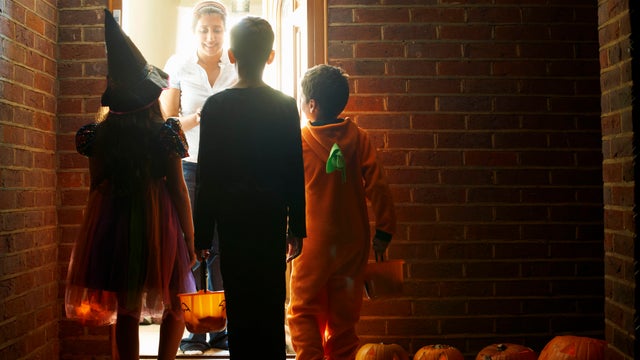 Rear view of three children wearing halloween costumes trick or treating