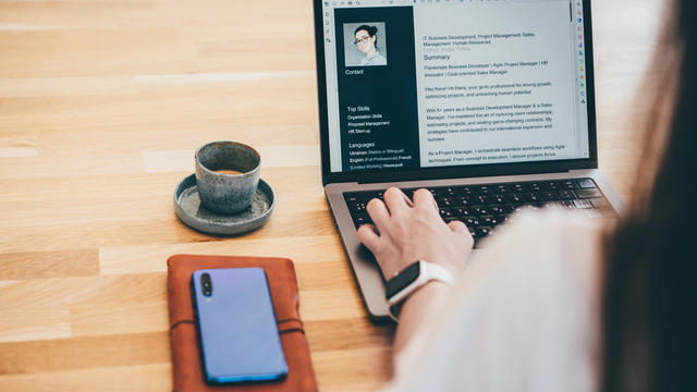 Young business woman searching for job online. Woman writing resume on laptop. 