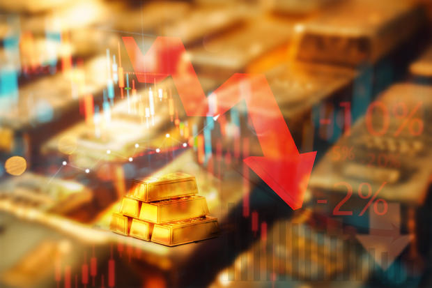 Financial downturn concept with gold bars and falling stock market graphs. 