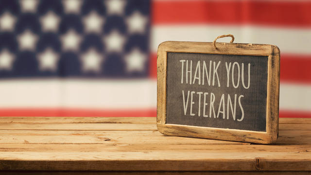 Veterans day background with chalkboard on wooden table and USA flag 