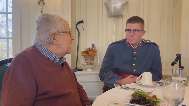 A male veteran speaks to a cadet, who is wearing his military uniform 