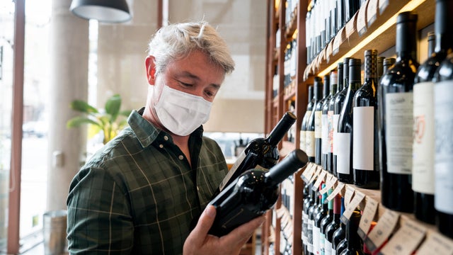 Man at a cellar buying a bottle of wine wearing a facemask 