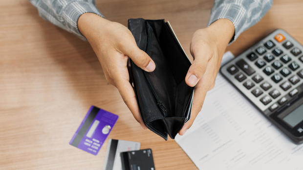 Poor man bankrupt with no credit in debt hand hold empty black leather wallet because economy down turn Empty wallet (no money) in the hands of an man, monthly bill expenses and credit card debt. 