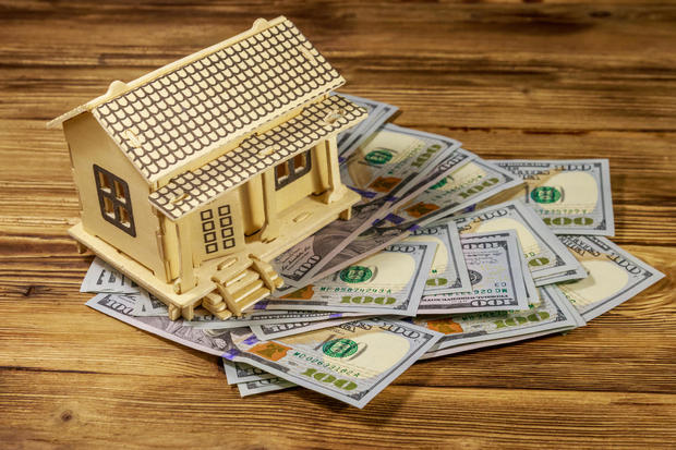 House model and U.S. one hundred dollar bills on wooden background. Property investment, home loan, house mortgage, real estate concept 