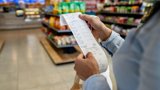 Woman shopping at a convenience store and checking her receipt 