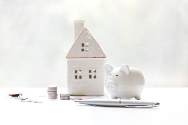 Model wood house and piggy saving with safety key for the investment of real estate. Copy space for tax. Real estate Concept