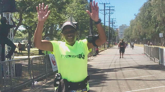 Denise Hall waves and smiles during a race 