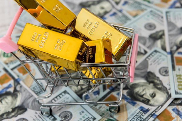 gold bars lie in a shopping cart, background with dollars. concept of money, wealth and abundance. 