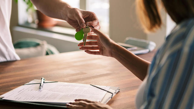 Cropped image of owner giving house keys to tenant after filling rental forms 