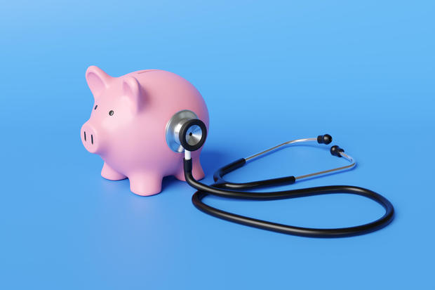 Black stethoscope on the body of a pink piggy bank in blue background. Illustration of the concept of financial health and long-term sustainability of a company 