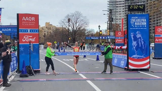 Katie Florio raises her arms as she breaks the tape at the Philadelphia Marathon 