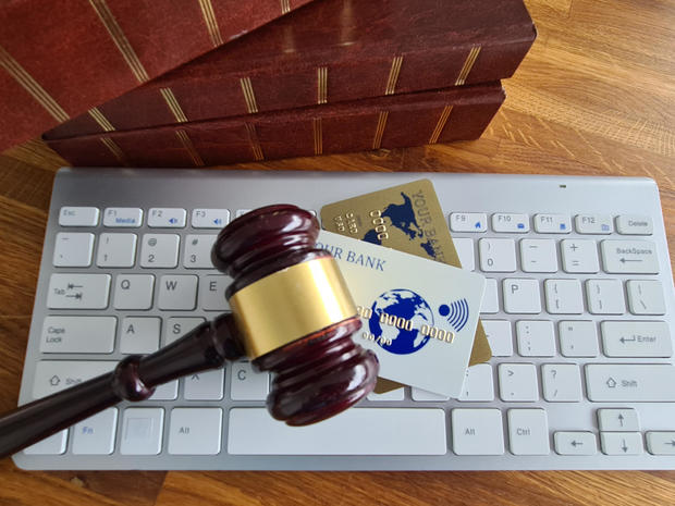 A gavel is placed on a computer keyboard next to several credit cards 