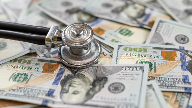 stethoscope on dollar banknotes as premium medical insurance concept. No people 