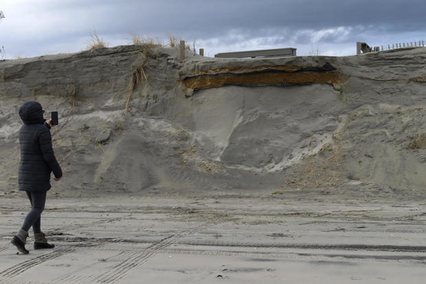 A beachgoer takes a photo of a severely eroded dune in North Wildwood, N.J. on Jan. 5, 2023 where a ramp down to the beach used to exist. 