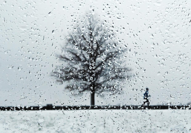 Snow falls as a women jogs at City Park in Denver 