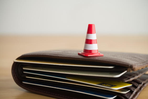 Close up red white traffic warning cones or pylon on leather wallet with many credit card. 