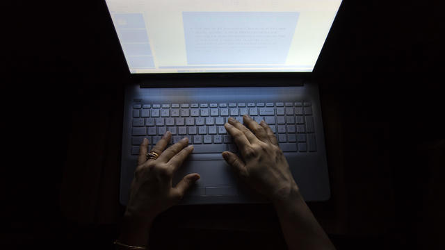 Female hands on a computer, working in the dark 