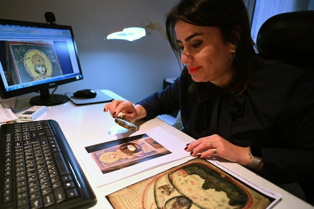 Christina Sotirakoglou a handwriting expert, observes Byzantine paintings based on photographs prints, at her office, in Thessaloniki, northern Greece, Saturday, Nov. 30, 2024