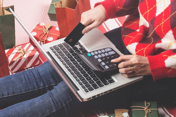 Christmas online shopping . Female buyer with laptop, prepare to xmas eve, sitting among gifts boxes and packages. Winter holidays sales