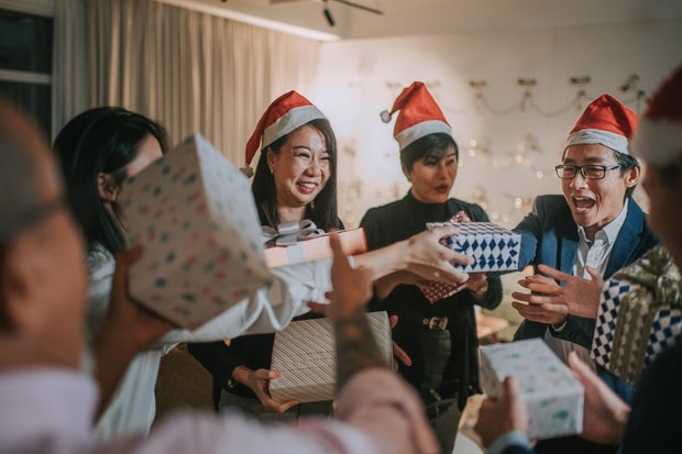 Asian Chinese office coworkers exchanging Christmas gifts while celebrating Christmas party after work hours in office lounge