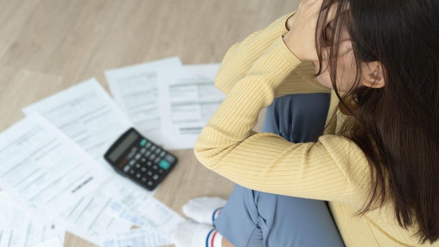 Women stress about a lot of credit card debt and bills on the floor. The housewife has trouble calculating monthly expenses and the budget is not enough to pay off the debt