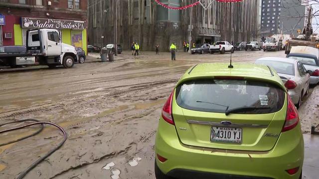 Mud covers Webster Avenue in the Bronx as damaged parked cars sit along the curb. 