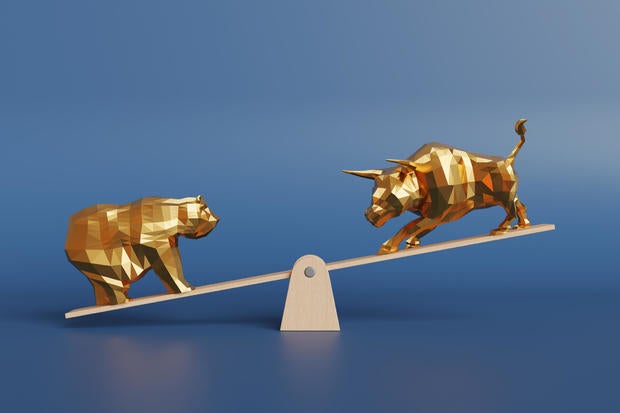 Gold bull and bear on each side of a wooden seesaw in gradient blue background. Illustration of the concept of bullish and bearish market, change of stock prices and risk of investment 