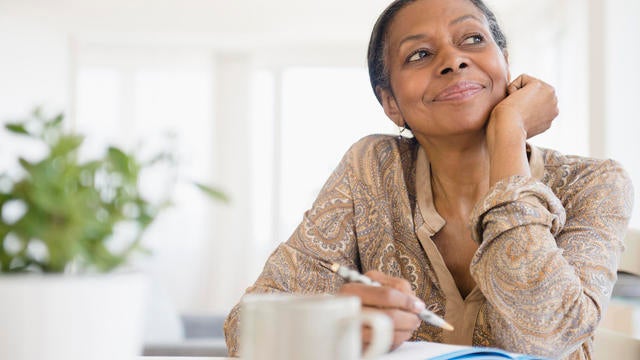 Mixed race woman writing at desk 