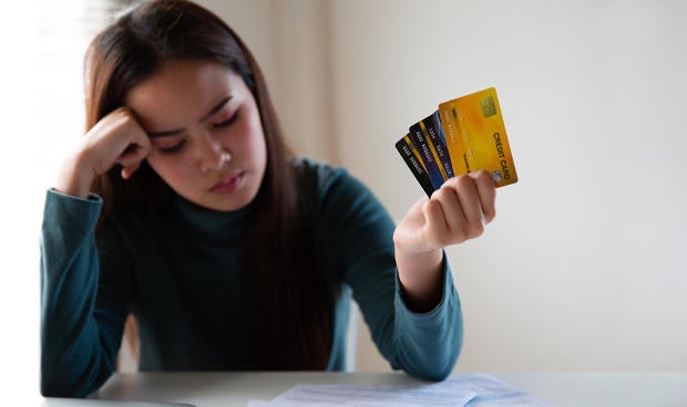 Stressed asian woman holding credit card and expenses bills paper. Woman having problem income. Unhappy woman without money to pay credit card. 