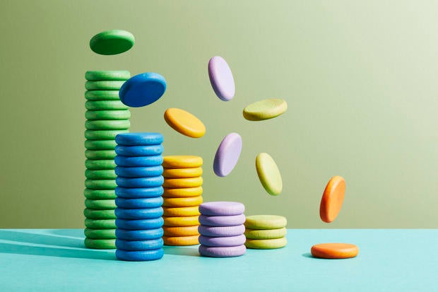 Six stacks of coloured coins with more coins falling onto them 