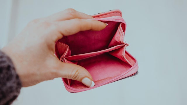 An elderly woman holds an open empty wallet in her hands, the concept of poverty, pensions 