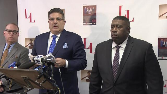 Former NYPD chief Jeffrey Maddrey stands next to his attorney, who stands behind a podium with several microphones on it. 