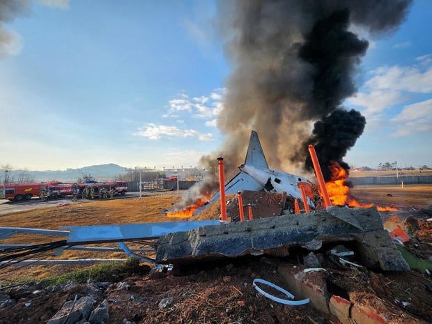 Firefighters carry out extinguishing operations on an aircraft which drove off runaway at Muan International Airport in Muan 