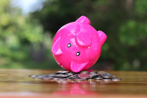 Piggy bank upside down on the pile of coins isolated on the table.