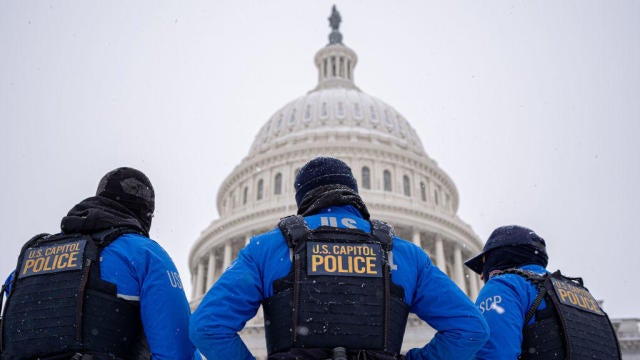 The dome of the U.S. Capitol Building is visible as U.S. Capitol Police officers stand guard in a winter storm in the nation's capital on Jan. 6, 2025. 