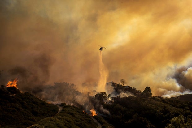 Water is dropped on the advancing Palisades Fire by helicopter on January 7, 2025.