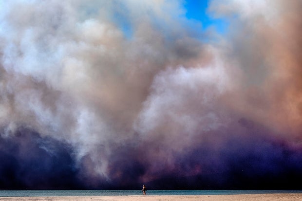 A black plume of smoke from Pacific Palisades passes over a beach in Santa Monica, California on January 7, 2025.