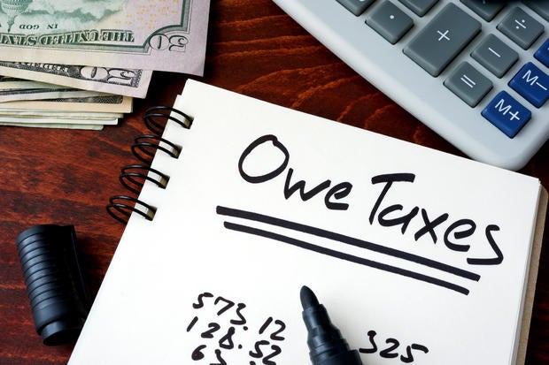 Notepad with sign Owe Taxes on a wooden background. 