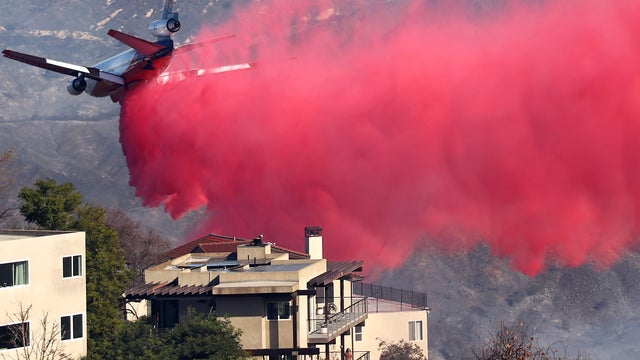 Firefighting aircraft drops pink flame retardant over a neighborhood in Los Angeles