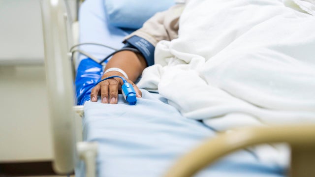 In the Hospital Sick Male Patient Sleeps on the Bed. Heart Rate Monitor Equipment is on His Finger. 