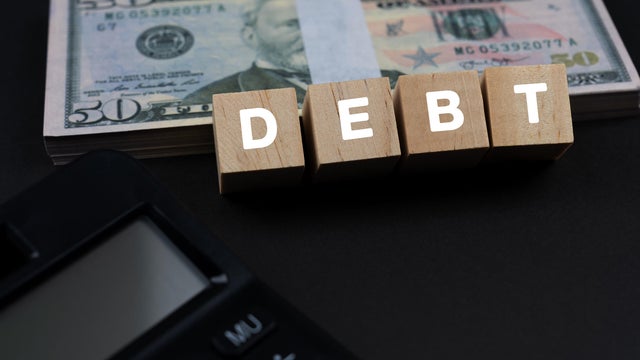 Debt Text On Wood Block With US Paper Currency and Calculator