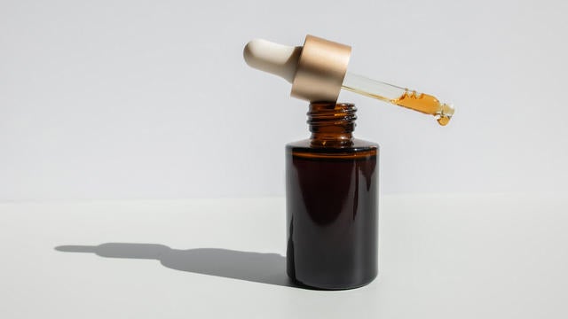 Brown glass with a dropper. Bottle mockup cosmetic oil dropper on a grey background and shadows. Copy space 